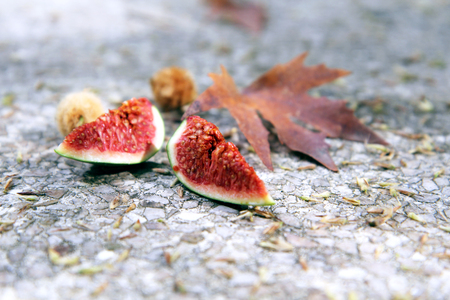 Two cut fig pieces and autumn leave on a stone backgroundの写真素材