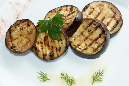 Grilled eggplants decorated with green leaf. Top view. White plate.の写真素材