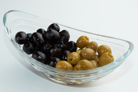 Pickled green and black olives in a glass bowl on white background.の写真素材