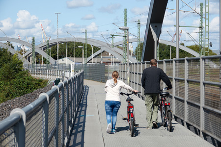 A married couple walking with bicycles on a bridge.の写真素材