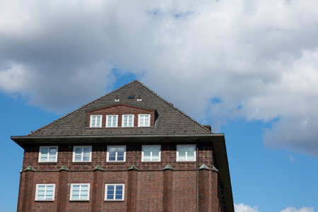 Roof of an old red brick house against a blue sky and clouds in Hamburg.の写真素材