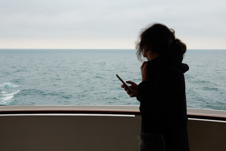 The girl uses cellular communication and the Internet on a smartphone in the sea on a cruise liner.の写真素材