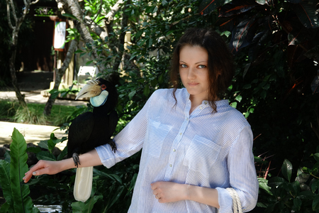 Beautiful girl holding a big bird Toucan on her hand.の写真素材