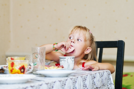 Little girl at the table eating sausageの写真素材