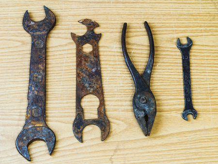 Rusty wrenches and pliers on a wooden surfaceの写真素材