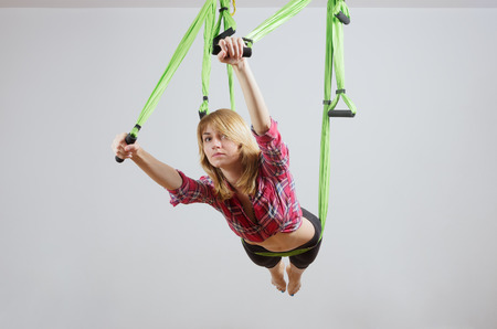 The girl performs exercises in a hammock for yoga / Photo taken in Russia, in the city of Orenburg, in the fitness clubの写真素材