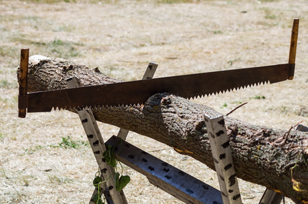 Two-handed saw in a beam on a trestle / Photo taken in Russia, in the courtyard of a rural houseの写真素材