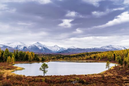 View of the Kidelu Lake and the snow-capped peaks of the Kurai ridge on the horizon. Autumn mountain landscape. Ulagansky District, Altai Republic, Russiaの写真素材