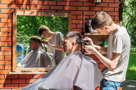 Orenburg, Russia - July, 20, 2019: Hairdresser cuts a man in an open air salon. FORMA MARKET - a city festival for the promotion of handmade designers, artisans and their projects with the aim of engaging in the business environmentのeditorial素材