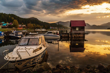Artybash village, Teletskoye Lake, Altai Republic, Russia - September, 21, 2019: Pleasure boats at the lake wharf with a wooden pier at dawnのeditorial素材