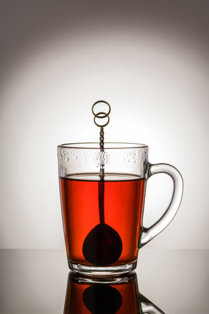 Black tea in a glass cup with a handle and a teaspoon.の写真素材