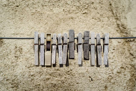 Old wooden clothespins hanging on a wire against a background of a plastered wall