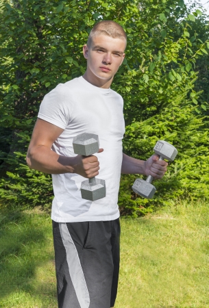 Teen lifting dumbbells outdoors  bicep curls の写真素材
