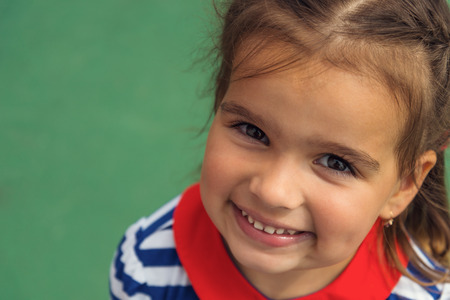 Close up of a smiling little girl on a green backgroundの写真素材