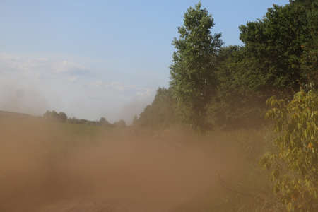 Dust along a dirt road near a field in summer.の写真素材