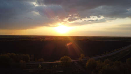 Sunset from a height among fields and trees. heaven and earth. orange sun.の写真素材