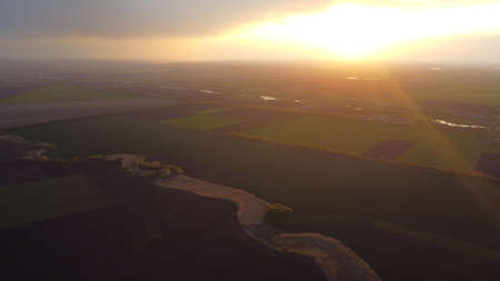 Sunset from a height among fields and trees. heaven and earth. orange sun.の写真素材