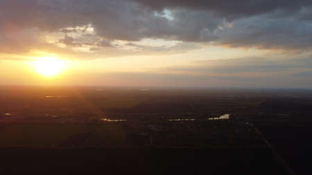 Sunset from a height among fields and trees. heaven and earth. orange sun.の写真素材