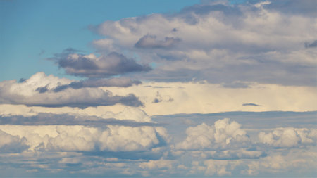 A vast sky filled with fluffy white clouds over a rural landscape.の写真素材