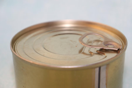 A metal can with a gold-colored lid, slightly tilted.