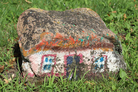 A painted rock with colorful graffiti on green grass.の写真素材