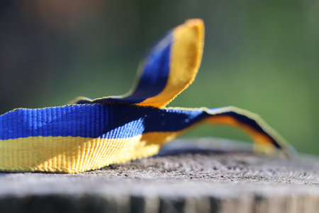 A torn blue-yellow ribbon placed on a rough wooden surface.の写真素材