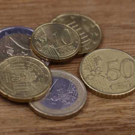 A pile of assorted euro coins stacked on a wooden surface.