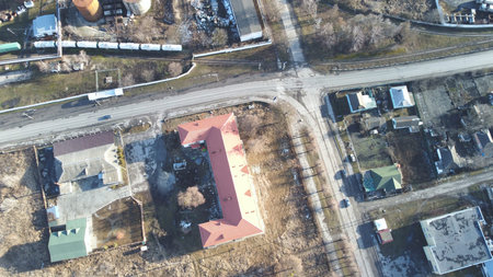 This aerial drone photograph captures a top-down view of a semi-rural landscape featuring a long...