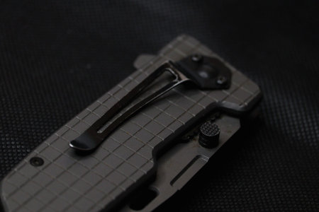 A close-up shot details the textured handle and pocket clip of a modern tactical folding knife...