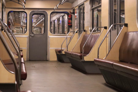 A view inside an old, empty Kyiv Metro train car with brown leather seats and beige walls,...