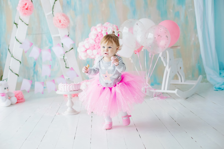 Baby girl 1 year old celebrating first birthday in room. Eating cake. Birthday decoration. Childhood.の写真素材
