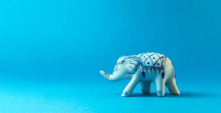 A ceramic elephant is walking on a blue background.の写真素材