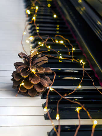 A piano is decorated with a lights garland and pine cone as decoration for Christmas and New Year.の写真素材