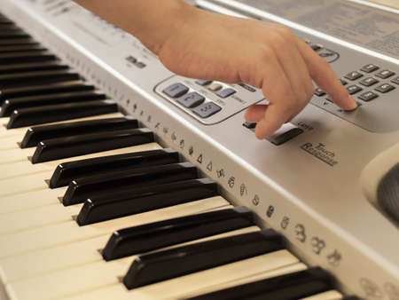 The hands of unrecognizable boy are playing old synthesizer.の写真素材