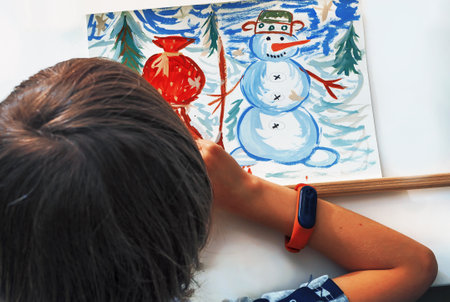 An unrecognizable caucasian child is drawing a Cristmas's picture. Home class. Directly above. Flat view.の写真素材