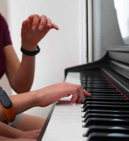 Piano private lesson. Young woman teaches a kid to play the piano. Playing together. Master teaches a boy to play piano. Concept of the music study and arts. Close-up. No faces.の写真素材
