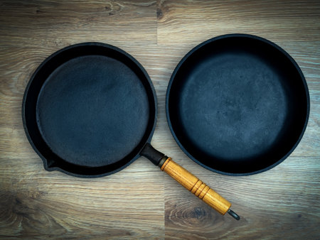 The two cast iron frying pans over the wooden background. Flat lay.の写真素材