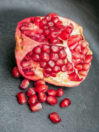 A piece of the pomegranate lying on a black granite plate. Close-up. Closeup.の写真素材
