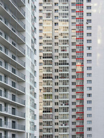 A large number of windows and balconies on building facade. Apartment block. Residental building....