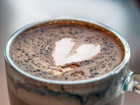 Cream heart pattern on the foam with cinnamon of latte coffee. Coffee latte glass. Close-up. Blurred background. Selective focus.の写真素材