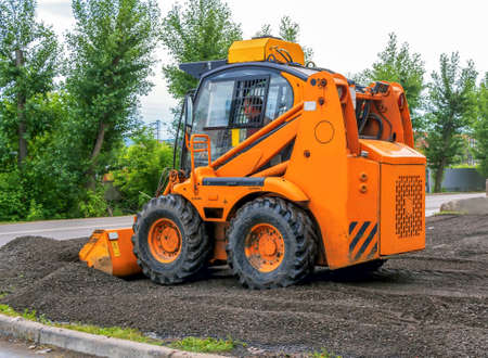 Orange color Skid steer loader with a many purpose bucket is using in landscaping.の写真素材