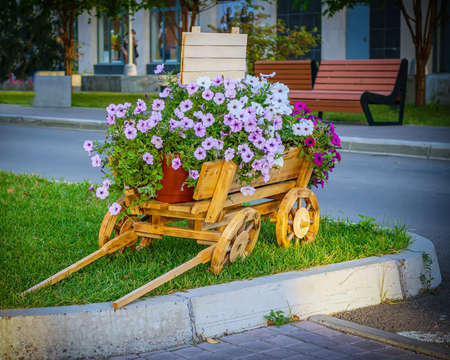 Flower bed designed like a small cart on a city street.