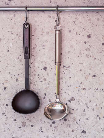 Black and shinyladles hang from a railing over a stone wall.の写真素材