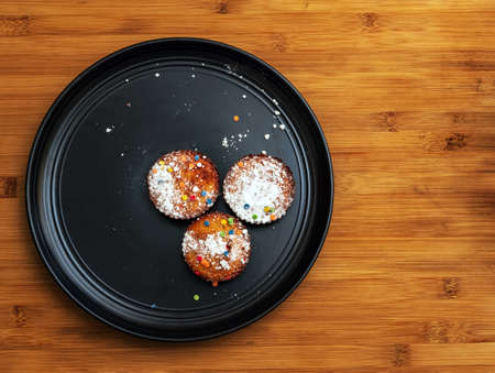 Low calorie gluten and lactose free cornmeal muffins with raisins and fructose sprinkle on a black plate. Healthy vegetarian desserts, dairy free. Home-made snack. Close-upの写真素材