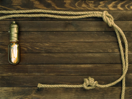 Wooden background made of dark brown boards with a glowing specular bulb and hemp ropes. Deck texture.の写真素材