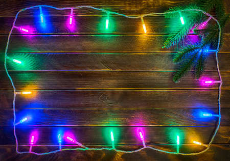 Frame of the christmas electric light garland on the dark wooden background.の写真素材