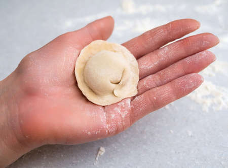 Hand of a girl holding a homemade dumpling in the palm Close-up. Homemade food.の写真素材