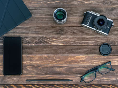 A set of the lens, camera, smartphone and tablet etc. on the wooden dark background. close-up. Flat...