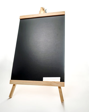 Black board with two pieces of chalks on wooden easel isolated on white background.の写真素材