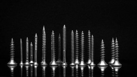 Kit of self-tapping screws on a black background with reflectionの写真素材